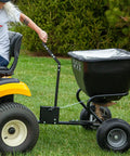 Deluxe Tow Behind Broadcast Spreader With Extended Easy Reach Handle And Weatherproof Cover, 175 Lb Capacity attached to tractor