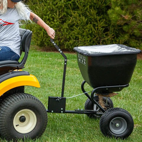 Deluxe Tow Behind Broadcast Spreader With Extended Easy Reach Handle And Weatherproof Cover, 175 Lb Capacity attached to tractor