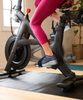 Cyclist using Peloton bike with sneakers in Toe Cages For Peloton Bike And Bike Plus Pedals Let You Ride In Sneakers No Fuss Shoes Delta Pedal Converter Aviation Aluminum Build Fits All Peloton Bikes And Makes Quick Shoe Swaps A Breeze.