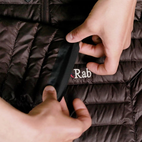 Applying Tenacious Tape Repair Patches Peel And Stick Nylon Gear Patches to a black nylon jacket showing hands holding a black patch.