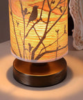 Birds In A Tree Wood Table Lamp With Wood Lampshade And Bronze Metal Base, lit on a table, 5 inch diameter, 9 inch height