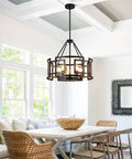 Twenty Inch Five Light Farmhouse Chandelier Featuring Walnut Wood And Matte Black Metal above a dining table in a bright room.