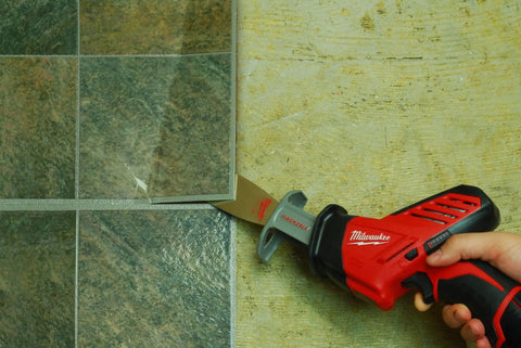 Electric tile cutter in use cutting through tile on floor