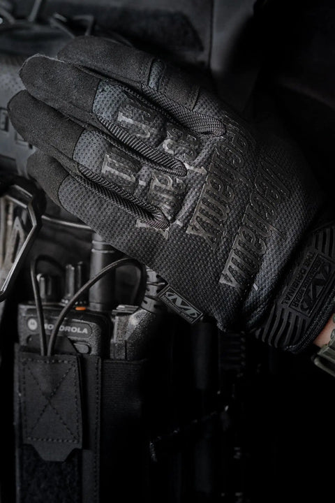 Covert Black Tactical Work Gloves With High Performance Anti Slip Grip And Touchscreen Capable, holding a radio.