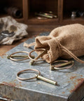Get Your Yard Gear Fixin' With These 12 Heavy Duty Carbon Steel Retaining Pins in a burlap sack on a metal surface.