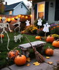 Halloween-themed front yard with skeletons, ghosts, pumpkins, and a broomstick, set for spooky outdoor decor