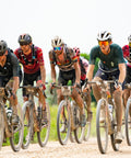 Cyclists on gravel road racing in a group, showcasing endurance riding on MTB and gravel bikes in a dirt track setting outdoors.