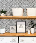 Laundry room with black and white peel and stick wallpaper with geometric chevron and herringbone pattern on wall behind wood shelves