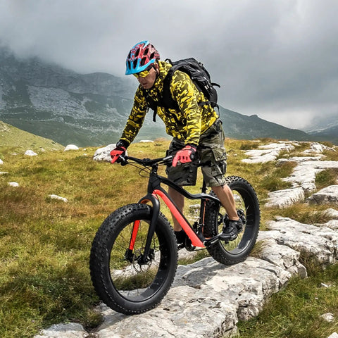 Cyclist rides fat bike with Fat Tire Front And Rear Wheelset For 20 24 26 Inch Bikes 4 Inch Wide Bead on rocky path