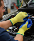 A person wearing Kevlar Tough Cut Resistant Work Gloves with PVC Grip ANSI Rated Heavy Duty Safety Gear handling a car battery.