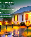 Six Pack Solar Torch Lights With Realistic Flickering Flame illuminating wet garden path, showcasing waterproof feature at night.