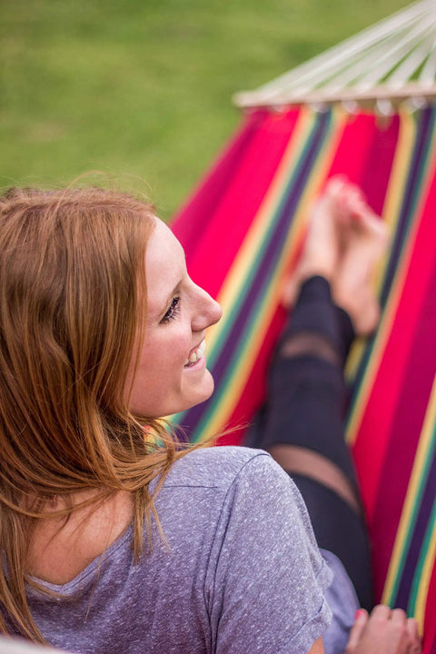 Woman relaxing in Cotton Blend Bahamas Hammock In Burgundy With Caribbean Colors Soft Cotton Fabric Hardwood Spreader Bars