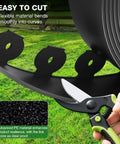 Close-up of cutting No Dig Landscape Edging Kit with scissors, showing flexible plastic material and landscaping spikes.