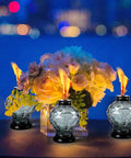 Four Pack Glass Table Torches With Citronella For Outdoor Patio And Garden on a table, surrounded by flowers, lit at night.