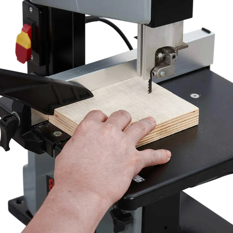 Badass Heavy Duty Steel Benchtop Band Saw With 2.2 Amp Motor cutting plywood with hand positioned on wood.