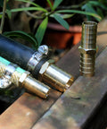 Solid Brass Garden Hose Repair Connector Kit with Half Inch Barb Fittings Dual Head Hose Repair Couplers Includes Stainless Steel Clamps Reusable 2 Pack for Lawn and Yard Watering Easy DIY Fix showing connectors and hose on a wooden surface.