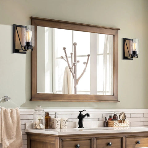 Bathroom with large wooden mirror, two wall sconces, and modern faucet above a wooden vanity.