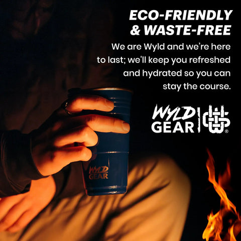 Person holding Wyld Gear party cup by a fire. Red 24 Oz Insulated Stainless Steel Party Cup With Lid No Sweat Double Wall Vacuum Insulated Tumbler.