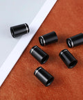 10 Pack.370 Golf Iron Ferrules With Black Body And Silver Ring scattered on a brown surface, highlighting tapered tip design.