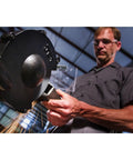 Man using Shop Ready Six Inch Bench Grinder Powered By A Half Horsepower Motor Spinning 3450 RPM Built Different With Heavy Cast Iron Frame.