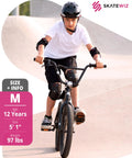 Person wearing knee and elbow pads riding a bicycle at skate park