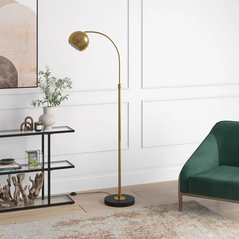 Arc Floor Lamp In Brass And Blackened Bronze For Living Room Bedroom Office And Dining Areas With Adjustable Head Two Tone Modern Pharmacy Style Eye Catching Minimalist Lighting Upgrade next to a green chair and shelf.
