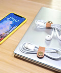 Leather Cord Organizer And Cable Keeper Case For Earbuds And Headphones on a desk with smartphone