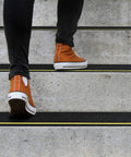 Person walking on stairs with 4 Inch By 33 Foot Anti Slip Tape With Reflective Stripe For High Traction On Stairs And Steps Black And Yellow Non Skid Grip Tape For Indoor Outdoor Use
