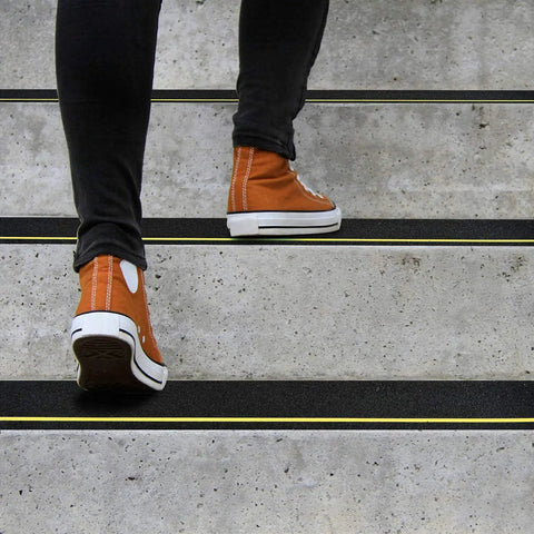 Person walking on stairs with 4 Inch By 33 Foot Anti Slip Tape With Reflective Stripe For High Traction On Stairs And Steps Black And Yellow Non Skid Grip Tape For Indoor Outdoor Use