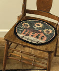 Round Chair Pad Featuring House And Sunflowers Folk Art Design on a wooden chair, showcasing 14.5 inch plush poly loop yarn.