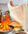 Person using Heavy Duty Fiberglass Fire Blanket 3.9 By 5.9 Feet For Emergency Survival And Kitchen Fire Safety Flame Retardant Heat Insulation Made For Grills Cars Camping And Home Use 5 Pack to extinguish kitchen fire
