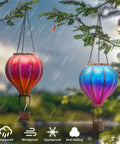 Set Of 2 Dope Hot Air Balloon Solar Lanterns For Outdoor Garden Decor glowing in rain, hanging among tree branches