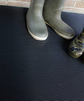 Heavy Duty Vinyl Round Rib Floor Mat For Tough Garages And Workshops Rock Solid One Eighth Inch Thick Build with green and camouflage boots on it.