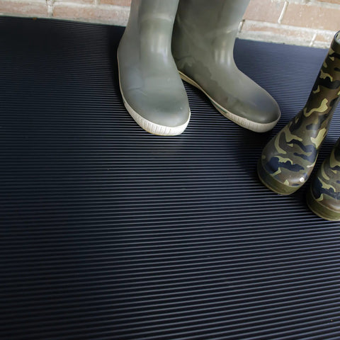 Heavy Duty Vinyl Round Rib Floor Mat For Tough Garages And Workshops Rock Solid One Eighth Inch Thick Build with green and camouflage boots on it.