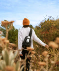 Person hiking with Roam 2 White Portable Waterproof Bluetooth Speaker With Crisp Clarity And Deep Bass, IP67 Durability on backpack
