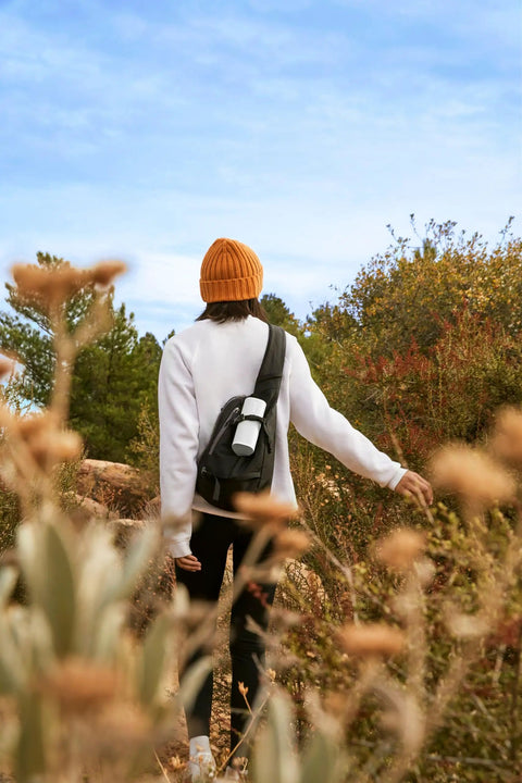 Person hiking with Roam 2 White Portable Waterproof Bluetooth Speaker With Crisp Clarity And Deep Bass, IP67 Durability on backpack