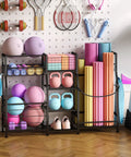 Home gym storage rack with weights, balls, yoga mats, and a variety of exercise equipment against a wall.