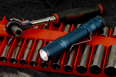 Blue Quark LED Flashlight Pocket EDC With Clip on tool rack with socket set, showcasing high CRI beam and compact design