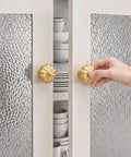 Solid Brass Cabinet Knobs And Gold Pumpkin Drawer Pulls Featuring Vintage Floral Accents For Kitchen Cupboards And Dressers Heavy Duty 6 Pack 1 1 8 Inch- A hand reaching for gold pumpkin cabinet knobs on modern glass cabinet doors.