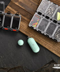 Assorted fishing tackle in transparent boxes on wood, including hooks, sinkers, and lures, optimized for saltwater fishing.