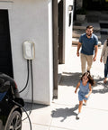 No Sweat Level 2 EV Charger 40 Amp 240V Home Wall Mount Electric Vehicle Plug In Station With Smart App Control And Rfid Card J1772 Nacs Super Quick Charge mounted on a wall outdoors near a family.