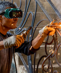 Workhorse Flip Up Welding Goggles With Impact Resistant Lenses on a mechanic welding metal, sparks flying, in a workshop setting.