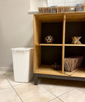 Solid Built 9 Gallon Under Sink Trash Can And Waste Basket For Kitchen Bathroom Or Office Room Featuring A Tough Reinforced Rim Plus Smooth Wipe Down Interior That Makes Spills An Absolute Breeze To Clean Up Today placed beside wooden shelving.