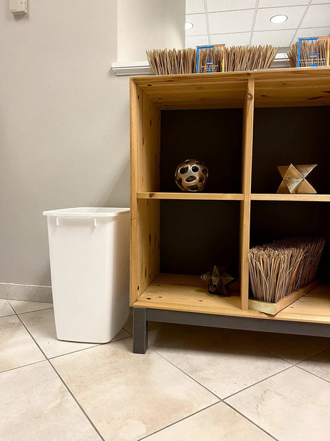 Solid Built 9 Gallon Under Sink Trash Can And Waste Basket For Kitchen Bathroom Or Office Room Featuring A Tough Reinforced Rim Plus Smooth Wipe Down Interior That Makes Spills An Absolute Breeze To Clean Up Today placed beside wooden shelving.