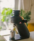 Game Changing Single Dose Coffee Grinder With 64 Millimeter Flat Burrs Stepless Adjustment, black design with stainless steel cup.