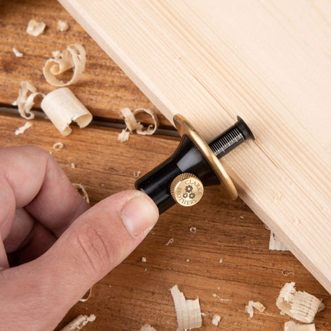 Hand holding Pro Grade Wheel Marking Gauge With Replacement Cutters, Woodworking Marking Scriber Kit against wood surface