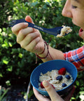 Person eating oatmeal with Four Blue Sporks To Go Set With Carrying Case 7 Inch Durable BPA Free 3 In 1 Camping Utensil Kit Spoon Fork And Serrated Knife For Camping Hiking Hunting And Outdoor Adventures.