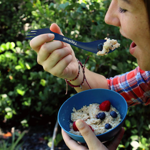 Person eating oatmeal with Four Blue Sporks To Go Set With Carrying Case 7 Inch Durable BPA Free 3 In 1 Camping Utensil Kit Spoon Fork And Serrated Knife For Camping Hiking Hunting And Outdoor Adventures.