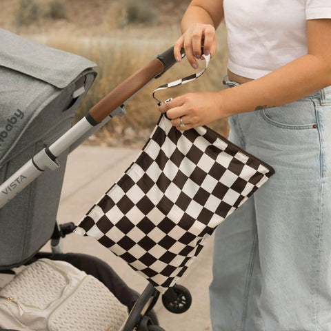 Person attaching Mess-Proof Wet Bag Set 2-Pack Reusable Waterproof Bags For Swimsuits And Baby Clothes On The Go to stroller.