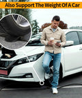 Man leaning on EV with coffee, using phone, foreground shows wheel on EV Charger Cable Protector For Garage Door Pass Through Built Tough Heavy Duty Cable Guard For Tesla All Models 3 Y X S And Mobile Connectors And Wall Chargers Stops Slips Bends Weather Wear And Trip Hazards.
